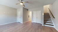 This two-story residence offers a thoughtfully laid-out floor plan with consistent, modern finishes throughout. Wood-look laminate flooring flows seamlessly across both levels, contributing to a clean and cohesive aesthetic. Neutral gray walls provide a versatile backdrop that complements the space's contemporary design.

The main level features a spacious living area illuminated by a ceiling fan with integrated lighting, along with access to a double-door closet and additional storage. The kitchen is a standout feature, showcasing rich dark espresso cabinetry, granite countertops, and a full suite of black appliances, including a refrigerator, gas range, dishwasher, and built-in microwave. The contrasting light flooring and sleek backsplash add visual depth to the kitchen's bold palette.

A full bathroom on this level includes a tub-shower combination, a dark-vanity with granite countertop, a large mirror, and tile flooring, maintaining the design consistency found throughout the home.

The upper level houses additional bedrooms, each finished with the same wood-look flooring and neutral tones. One bedroom features a window with natural light and views of the surrounding neighborhood, while another includes a ceiling fan. A separate walk-in shower bathroom serves the upper level. A staircase with wood treads and a railing connects both floors, adding a refined structural detail to the interior.