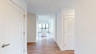 Located at 1991 Main St in the heart of downtown Sarasota, Florida, this sophisticated two-story residence offers a thoughtfully designed open layout across two generously proportioned floors. The main level centers around a seamless kitchen and living area, where the kitchen impresses with flat-front cabinetry in a warm wood finish, sleek white upper cabinets, a clean white backsplash, stainless steel drawer dishwasher, and an integrated sink with brushed gold fixtures. A central island anchors the space, which flows directly toward floor-to-ceiling black-framed windows that frame sweeping views of the Sarasota cityscape and palm-lined streets below. The living room features dramatic double-height glazing that floods the interior with natural light and creates a striking sense of volume. Wide-plank wood flooring runs continuously throughout both levels, lending warmth and cohesion to the modern aesthetic. The three bedrooms are generously sized, each bright and airy, complemented by six well-appointed bathrooms featuring marble-look tile flooring, light wood vanities with white quartz countertops, framed mirrors, and glass-enclosed showers with brushed gold hardware. Spacious walk-in closets with built-in shelving and rail systems provide ample storage. Two balconies extend the living space outdoors, offering open-air access to Sarasota's vibrant urban surroundings.