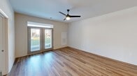 Located at 1000 Lassen Dr in Knightdale, NC, this well-appointed 2-bedroom, 2-bathroom unit offers a thoughtfully designed layout across a single floor. The open-concept kitchen and living area serves as the heart of the home, featuring warm hardwood-style flooring, recessed lighting, and pendant lights above a sleek white kitchen island with an undermount sink. The kitchen is equipped with white shaker cabinetry, quartz countertops, stainless steel appliances including a refrigerator and electric range, and a modern wall-mounted range hood. French doors in the living room invite natural light and provide outdoor views, complemented by a ceiling fan with a light fixture. Both bedrooms are carpeted and feature ceiling fans and windows that allow ample natural light. The generously sized primary bedroom includes a dedicated walk-in closet outfitted with multi-level wire shelving and hanging rods for efficient storage. A second walk-in closet offers similarly practical organization. The bathrooms are clean and functional, with one featuring a tub-shower combination, hardwood-style flooring, and crisp white finishes. The unit presents a modern, neutral aesthetic throughout, making for a comfortable and versatile living space.