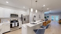 Located at 101 Haven Blvd in Palm Coast, Florida, this well-appointed single-story, 2-bedroom, 2-bathroom home offers a thoughtfully designed layout with modern finishes throughout. Light wood-tone flooring flows seamlessly across the entire space, lending a clean, cohesive aesthetic.

The open-concept kitchen is a standout feature, boasting white shaker cabinetry, quartz countertops, stainless steel appliances, and a central island with bar seating illuminated by stylish pendant lighting. The kitchen opens directly to the dining area and living room, creating an ideal space for entertaining. The living room offers access to a private patio through French doors, bringing in natural light and outdoor connectivity. An in-unit stacked washer and dryer is conveniently located near the kitchen.

The primary bedroom is generously sized, featuring a ceiling fan, a window with outdoor views, and direct access to a well-finished ensuite bathroom. The ensuite includes a single vanity with white cabinetry, quartz countertop, and a large mirror. The second bathroom features a tub-shower combination with a sliding glass door and matching white vanity. Both bedrooms benefit from ample closet space. The home's neutral gray-toned walls and recessed lighting throughout create a bright, contemporary atmosphere.