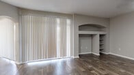 Located at 12401 W Hillsborough Ave in Tampa, Florida, this two-story residence offers a well-designed layout with a mix of functional and stylish finishes throughout. The living area is highlighted by rich, dark wood-look flooring, a large sliding glass door with vertical blinds that allows ample natural light, and a distinctive arched built-in shelving nook that adds architectural character to the space. A ceiling fan overhead enhances comfort in the generously sized secondary living area, which also features the same durable wood-look flooring and an arched passageway leading to adjacent rooms. The kitchen is equipped with stainless steel appliances, including a refrigerator, range, microwave, and dishwasher, complemented by crisp white cabinetry, light quartz-style countertops, and a classic subway tile backsplash. A decorative wine rack detail adds a charming touch. The bedrooms are carpeted for comfort and include ceiling fans and ample closet space. The bathrooms feature wood-look tile flooring, soaking tubs with checkered tile surrounds, white vanities with stone countertops, and large mirrors. A dedicated in-unit laundry room with overhead shelving provides added convenience. Throughout, neutral tones and clean finishes create a cohesive and inviting atmosphere.