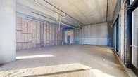 Located at 850 S Gaines St in Tallahassee, FL, this single-floor commercial shell space presents a substantial open floor plan ready for a custom tenant build-out. The interior is currently in raw shell condition, featuring exposed concrete ceilings and structural columns that give the space an industrial character. Roughed-in plumbing and electrical conduit are visible overhead, indicating that core utilities infrastructure is already in place. Insulation batts are installed within the framed wall sections, providing a foundation for future interior finishing.

The perimeter of the space features large floor-to-ceiling glass storefronts and sliding glass doors on multiple sides, allowing abundant natural light to pour in and offering clear views of the surrounding Tallahassee streetscape and neighboring developments. These expansive glazed facades also provide excellent street visibility, making the space well-suited for retail, restaurant, or service-oriented commercial uses.

The layout is entirely open and unobstructed, affording maximum flexibility for interior configuration. A separate entry door is also present alongside the storefront glazing. The space is situated within what appears to be a modern mixed-use development, benefiting from an urban setting with strong pedestrian access and surrounding amenities.