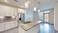 Located at 9779 Fannin Railway in Houston, TX 77045, this one-bedroom, one-bathroom unit offers a thoughtfully designed single-floor layout that maximizes every square foot. The open-concept kitchen and living area serves as the heart of the home, anchored by a striking granite-topped center island with an undermount sink and stylish pendant lighting overhead. White shaker cabinetry lines the kitchen walls, complemented by a tile backsplash, under-cabinet lighting, and a full suite of stainless steel appliances including a french door refrigerator with ice maker, range, microwave, and dishwasher. Light wood-look flooring runs throughout the main living areas, enhancing the bright, airy feel of the space. Large windows in the living area invite natural light and provide views of the surrounding neighborhood. The bedroom is a comfortable retreat finished with plush wall-to-wall carpet, a ceiling fan, and a generous window. A dedicated closet provides ample storage. Additional conveniences include an in-unit laundry area and a private patio, ideal for outdoor relaxation. The clean, neutral palette throughout creates a modern and welcoming ambiance suited for everyday living.