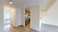 Located at 1810 Almaden Rd in San Jose, California, this single-floor unit offers a straightforward, functional layout designed for comfortable everyday living. The space is characterized by a consistent use of wood-look laminate flooring throughout the main living and kitchen areas, lending warmth and visual continuity across the open floor plan.

The kitchen is semi-enclosed, accessible through a wide doorway and partially open to the living area via a raised counter bar. It is equipped with stainless steel appliances, including a refrigerator and an electric range with a ventilation hood above. Warm-toned wood cabinetry extends to the upper walls, providing generous storage, while light-colored countertops offer a clean, practical work surface.

The living area is spacious and open, with neutral white walls and a seamless flow toward the kitchen. A window brings in natural light, and a baseboard heating unit runs beneath it. The bedroom features plush wall-to-wall carpeting and crisp white walls, creating a quiet, comfortable retreat.

The bathroom is well-appointed with a full-size tub and shower combination, a wide vanity with warm wood cabinetry, a large mirror, and wood-look tile flooring. Overall, the unit presents a clean, move-in ready environment with practical finishes throughout.