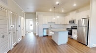 This single-story, 3-bedroom, 2-bathroom home offers a thoughtfully designed layout that maximizes comfort and functionality. The open-concept kitchen and living area serves as the heart of the home, featuring crisp white shaker cabinetry, a white subway tile backsplash, granite countertops, stainless steel appliances, and a generously sized center island with pendant lighting overhead. Warm-toned luxury vinyl plank flooring flows seamlessly throughout the entire home, lending a cohesive and contemporary feel.

The bedrooms are bright and airy, each equipped with ceiling fans, recessed lighting, and windows fitted with blinds that allow natural light to filter in. The primary bedroom offers a comfortable footprint with access to ample closet space. In total, five closets are distributed across the home, providing exceptional storage capacity.

Both bathrooms are finished with granite-topped white vanities and brushed nickel hardware. One bathroom features a full tub-shower combination with white tile surround. A dedicated laundry room adds everyday convenience. The living area includes a front entry door with a sidelight window, adding a welcoming touch. Throughout the home, neutral walls, clean lines, and modern fixtures create a bright, move-in-ready atmosphere.