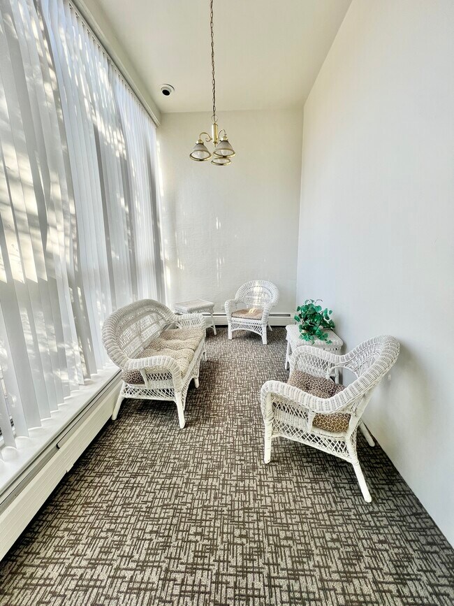 Encantadora terraza acristalada con muebles de mimbre blanco y alfombras suaves, que disfruta de mucha luz natural. - Rhapsody Apartments