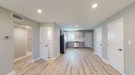 Located at 6037 Barton Dr in Shawnee, Kansas, this single-floor space presents a clean, modern aesthetic highlighted by light wood-look luxury vinyl plank flooring that runs seamlessly throughout every room. Soft gray walls and crisp white trim create a cohesive, neutral palette that enhances the sense of openness across the layout.

The kitchen serves as a functional centerpiece, outfitted with gray shaker-style cabinetry, white countertops, and a classic white subway tile backsplash. A full suite of stainless steel appliances—including a refrigerator, electric range, over-the-range microwave, and dishwasher—provides a polished, move-in-ready appeal. A window above the sink introduces natural light, while recessed ceiling lighting ensures the space remains bright.

The open living and main areas are generously proportioned, with recessed lighting overhead and multiple doorways providing access to additional rooms. Two well-sized bedrooms each feature ceiling fans with light fixtures and windows fitted with white blinds, offering natural light and ventilation.

The bathroom is tastefully updated with marble-style tile on the floors and tub surround, a wall-mounted gray vanity with a white basin, brushed nickel fixtures, and a framed mirror. A dedicated laundry area is also present within the unit. The overall design is clean, contemporary, and functional throughout.