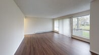 Located at 25246 106th Ave SE in Kent, WA, this single-floor residence offers a practical and comfortable layout with a cohesive, clean aesthetic throughout. Rich wood-style flooring runs continuously across the main living areas, complemented by neutral-toned walls and textured ceilings that add warmth and character.

The spacious living room is a standout feature, bathed in natural light through large sliding glass doors fitted with vertical blinds that open directly onto a private balcony. A baseboard heating system ensures year-round comfort. The adjoining dining area flows naturally from the living space, creating an open and functional common area.

The galley-style kitchen is efficiently designed, featuring white cabinetry with ample upper and lower storage, granite-patterned countertops, a full suite of white appliances including an electric range, microwave, and refrigerator, and a single-basin sink. Wood-style flooring continues here, maintaining visual consistency throughout.

The bedroom offers a quiet retreat with a window dressed in vertical blinds, baseboard heating, and direct access to the hallway. The bathroom includes a full tub and shower combo with white tile surround, brushed nickel fixtures, and wood-style flooring. Three closets provide generous storage options throughout the unit.