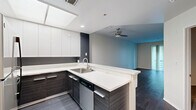 Located at 600 S Curson Ave in Los Angeles, this well-appointed one-bedroom, one-bathroom residence offers a thoughtfully designed layout with modern finishes throughout. The open-concept living and kitchen area is anchored by dark hardwood flooring that extends across the main living spaces, creating a sleek and cohesive aesthetic. A ceiling fan overhead and a sliding glass door leading to a private balcony provide both comfort and an abundance of natural light.

The kitchen is a standout feature, showcasing two-tone cabinetry with crisp white upper cabinets and dark wood-grain lower cabinets, complemented by clean white countertops and a peninsula that opens to the living area. Stainless steel appliances, including a refrigerator, microwave, and dishwasher, complete the contemporary culinary space. A skylight above adds brightness to the kitchen.

The bedroom is generously sized, finished with plush carpeting and direct access to the full bathroom. The bathroom is outfitted with a floating dark wood vanity, white countertop, a combination tub and shower, and wood-look flooring. Additional storage is provided by three closets located throughout the residence. A hallway connects the living areas to the private spaces, and built-in cabinetry in the living room adds practical storage with a refined touch.