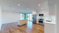 Located at 901 Vine St in the heart of Hollywood, Los Angeles, this modern single-floor unit offers a clean, contemporary design with high-quality finishes throughout. The open-concept living and kitchen area is anchored by warm hardwood flooring and bathed in natural light from large floor-to-ceiling sliding glass doors that lead to a private balcony overlooking lush greenery. Recessed lighting complements the bright, white interiors throughout the space.

The kitchen is outfitted with sleek white flat-front cabinetry extending to the ceiling, white quartz countertops, a glass tile backsplash, and a full suite of stainless steel appliances including a gas range, microwave, dishwasher, and French door refrigerator. A movable kitchen island with a light wood finish provides additional workspace and storage flexibility.

The bathroom features elegant marble-style tile surrounding the soaking tub and shower, complemented by warm mosaic floor tile, a long floating white vanity, and large wall mirrors. Bedroom spaces are carpeted for comfort and include mirrored closet doors, recessed lighting, and windows with outdoor views. The unit's crisp white walls and modern design create a bright, versatile living environment well-suited to the vibrant Hollywood neighborhood.