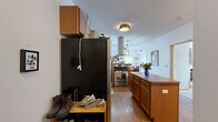 Located at 3020 University Ave SE in Minneapolis, this two-bedroom, one-bathroom residence offers a functional and well-designed single-floor layout. The open-concept kitchen and living area serves as the heart of the home, featuring warm wood cabinetry, stainless steel appliances, a central island with counter seating, and a striking stainless range hood as a focal point. Hardwood-style flooring flows through the kitchen and living areas, while pendant lighting adds a welcoming ambiance. The living room is generously sized and bathed in natural light from multiple windows that frame urban views of the Minneapolis skyline and surrounding neighborhood. Both bedrooms are carpeted and offer ample natural light through large windows, also with city views. The primary bedroom includes a built-in closet with shelving for organized storage. The full bathroom features tile flooring, tile wainscoting, a wide vanity with under-sink cabinetry, a large mirror, and a shower-tub combo. Throughout the residence, clean white walls and consistent finishes create a cohesive, comfortable living environment well-suited to urban life near the University of Minnesota.