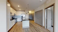 This well-appointed 1-bedroom, 1-bathroom residence offers a thoughtfully designed single-floor layout that maximizes both functionality and comfort. The open-concept kitchen serves as the heart of the home, showcasing crisp white shaker cabinetry extending to the ceiling, a classic subway tile backsplash, and sleek dark granite countertops. A central island with a matching granite surface provides additional prep and gathering space, illuminated by stylish industrial-style pendant lights. The kitchen is fully equipped with a stainless steel appliance suite, including a French door refrigerator with ice dispenser, a range, and a built-in microwave. Light wood-style plank flooring flows seamlessly throughout the main living areas, complementing the neutral color palette. The bedroom offers a comfortable retreat with natural light streaming through window blinds, a ceiling fan for year-round comfort, and direct access to the bathroom. The bathroom features white cabinetry topped with dark granite countertops, an undermount sink, and a large mirror, with a walk-in closet conveniently adjacent. Gray interior doors and recessed lighting complete the modern, cohesive aesthetic of this move-in-ready residence.