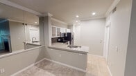 Located at 3601 Grapevine Mills Pkwy Frontage Rd in Grapevine, TX, this single-floor residence offers a well-designed layout that balances functionality and comfort throughout. The kitchen is a standout feature, showcasing granite countertops with an integrated sink, white cabinetry with glass-front upper cabinets, a subway tile backsplash, and a full suite of stainless steel appliances including a refrigerator with ice and water dispenser, electric range, and built-in microwave. A peninsula counter extends into the living area, creating a natural transition between the kitchen and the carpeted living space. Crown molding runs throughout the main living areas, adding a refined architectural detail to the neutral-toned walls and recessed lighting overhead. The bedroom is generously sized, featuring plush carpet flooring, a ceiling fan with light fixture, and a window fitted with blinds that allows natural light and outdoor views of surrounding greenery. The bathroom includes a full tub and shower combination with white tile surround, complemented by tile flooring and a toilet. Tile flooring is present in the kitchen and bathroom areas, while carpet covers the living and bedroom spaces. The overall ambiance is clean, bright, and move-in ready, offering a comfortable living environment in a convenient Grapevine location.