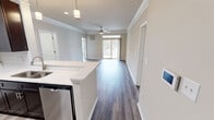 Located at 3100 Ashley Town Center in Charleston, SC, this single-floor residence offers a well-designed, open-concept layout that seamlessly connects the living, dining, and kitchen areas. The living room is finished with wood-style flooring, crown molding, a ceiling fan, and recessed lighting, creating a bright and welcoming atmosphere. A sliding glass door leads to a private balcony, allowing natural light to flow freely throughout the space.

The kitchen is a standout feature, equipped with rich dark espresso cabinetry, stainless steel appliances including a refrigerator, range, and microwave, and a generous quartz peninsula with an undermount sink and pendant lighting above—ideal for both everyday cooking and casual dining.

The bedrooms are carpeted for comfort and include ceiling fans and windows with outdoor views of the surrounding greenery. The bathrooms are finished with dark vanity cabinetry, white quartz countertops, and wood-style flooring. One bathroom features a tub-shower combination with white tile surround and brushed nickel fixtures, while another offers a spacious vanity with a large mirror and strip lighting. Throughout, neutral tones, clean lines, and consistent finishes contribute to a cohesive and modern aesthetic.