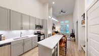 Located at 2219 E 11th St in Tulsa, Oklahoma, this one-bedroom, one-bathroom residence makes a striking first impression with its dramatically tall ceilings that lend a sense of openness well beyond its compact footprint. Light-toned walls and light wood-style flooring flow throughout the main living area, enhancing the airy atmosphere.

The open-concept kitchen is outfitted with sage-gray shaker cabinetry, white quartz countertops, a classic subway tile backsplash, and stainless steel appliances. A peninsula island with seating provides a natural gathering point and transitions seamlessly into the living area. A built-in desk nook adjacent to the kitchen offers a dedicated and efficient workspace.

The living room benefits from tall windows that draw in natural light and frame exterior views, creating a bright and welcoming environment. The bedroom continues the lofty ceiling aesthetic, features plush carpet flooring, and is illuminated by multiple windows with views to the exterior.

The bathroom is finished with hexagonal tile in the tub-shower surround, a white vanity with integrated sink, and wood-style flooring for a clean, contemporary look. A closet completes the layout, providing practical storage within this well-designed Tulsa residence.
