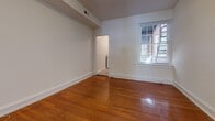 Located in Richmond, Virginia's vibrant neighborhood along W Grace Street, this single-floor unit blends classic architectural character with functional living spaces. Rich hardwood flooring flows throughout the main living and bedroom areas, lending warmth and a timeless aesthetic to the interior. White trim and baseboards provide clean contrast against the neutral walls, creating a bright and cohesive atmosphere.

The living spaces are well-lit by multiple windows dressed with blinds, allowing natural light to filter through while offering views of the surrounding streetscape and greenery. Ceiling fans in the main rooms provide added comfort and airflow. The entry features a glass-panel door with a transom window above, welcoming natural light into the front of the unit.

The kitchen is efficiently designed with white cabinetry above and below, dark countertops, a double-basin stainless steel sink, a gas range, and a dishwasher. Light vinyl flooring grounds the space practically. The bathroom is a standout, featuring a classic clawfoot soaking tub with an overhead shower fixture and a striking black-and-white checkered tile floor, evoking vintage charm. Throughout, the layout flows naturally from room to room, offering a comfortable and characterful living experience.