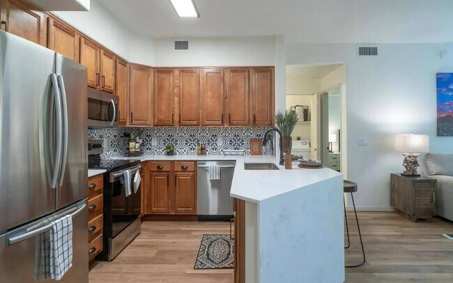 Cocina abierta con isla de estar y gabinetes de madera - Desert Parks Vista