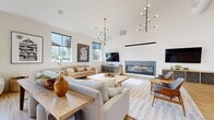 Located at 7900 SE Luther Road in Portland, OR, this 1,130-square-foot single-floor space is a thoughtfully designed modern gathering area that blends open-plan living with versatile functionality. The room is anchored by dramatic vaulted ceilings that amplify its sense of scale, while crisp white walls and warm honey-toned hardwood flooring create a bright, welcoming atmosphere throughout.

A sleek, wall-mounted linear gas fireplace serves as a focal point on one end, flanked by a stylish wood-and-slate media credenza with an wall-mounted flat-screen television above. Opposite, a floor-to-ceiling black-framed glass partition wall separates a dedicated meeting or dining area, furnished with a large wooden table and modern chairs, while maintaining visual connectivity across the entire space.

The main lounge area features a comfortable seating arrangement with mid-century modern accent chairs, a sofa grouping, and layered area rugs. A second casual lounge zone near large windows provides abundant natural light and outdoor views. The space is further enhanced by a striking branched chandelier and pendant lighting throughout.

Large glass sliding doors open to an outdoor area, seamlessly connecting interior and exterior spaces. A row of framed artwork adds a curated, residential quality, making this a highly functional and aesthetically refined communal space.
