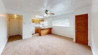 Located at 1404 Pacific Ave in Natrona Heights, Pennsylvania, this single-floor unit offers a practical and functional layout throughout. The entry foyer greets visitors with stone-look tile flooring and clean white walls, providing a welcoming transition into the main living spaces.

The kitchen is a standout feature, equipped with warm honey-toned wood cabinetry, dark laminate countertops, and white appliances including a range, microwave, and refrigerator. A peninsula island adds additional counter space and acts as a natural divider between the kitchen and the open living area. Stone-look tile flooring continues through the kitchen, while two windows allow ample natural light to fill the space.

The living area is generously sized and finished with plush wall-to-wall carpeting. A ceiling fan with integrated lighting provides both comfort and illumination, and additional windows bring in natural light while offering views of the surrounding greenery.

The bedroom is a quiet, well-proportioned room with soft carpet underfoot and a window fitted with blinds for privacy and light control. The bathroom includes a clean, full-sized tub and shower combination with chrome fixtures set against crisp white surrounds.

Overall, the unit presents a straightforward and comfortable layout, well-suited for everyday living.