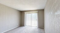 This single-floor, one-bedroom, one-bathroom unit offers a practical and functional layout across a compact but efficient footprint. The combined living and dining room serves as the heart of the space, featuring neutral-toned carpet flooring, textured walls, and a large sliding glass door fitted with vertical blinds that fills the area with natural light and provides access to the outdoors.

The kitchen is outfitted with warm-toned wooden cabinetry extending to the upper walls, offering generous storage alongside a pantry for additional organization. Black appliances — including a refrigerator, dishwasher, and electric range — complement the light countertops, while wood-look vinyl flooring grounds the space.

A carpeted hallway connects the main living areas to the private spaces, lined with closet access and louvered doors for added storage convenience. The bedroom is a well-proportioned retreat with plush carpet, textured walls, and a window with outdoor views, allowing natural light to filter through.

The bathroom features a full tub-shower combination, a white vanity with storage, and wood-look flooring, maintaining a clean and bright aesthetic. A utility room and dedicated pantry round out the functional offerings of this efficiently designed unit, making it a highly practical living space.