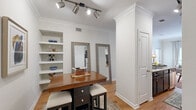 This single-floor, 2-bedroom, 1-bathroom residence offers a thoughtfully designed layout that maximizes every square foot. The living room features crown molding, light hardwood flooring, and large windows that invite abundant natural light, creating a bright and welcoming atmosphere. The space opens toward the kitchen, which is outfitted with dark espresso cabinetry, stainless steel appliances including a refrigerator, microwave, and range, granite countertops with a double sink, and a tasteful tile backsplash that adds a modern touch.

A dedicated dining area sits adjacent to the kitchen and features built-in open shelving, track lighting, and a column architectural detail that adds character to the space. Two full-length mirrors further enhance the sense of openness in this area.

The primary bedroom is a comfortable retreat with plush carpet, a window with natural light, and neutral tones that promote a calm ambiance. The second bedroom is similarly appointed with soft carpet and natural light. The shared bathroom features wood-look flooring, dark cabinetry with a vessel sink, a large framed mirror, and a shower-tub combination. Throughout the residence, crisp white walls and consistent trim work create a cohesive, polished aesthetic.