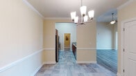 This single-story residence in Wake Forest, NC offers a well-organized layout designed for comfortable everyday living. The interior is finished in warm neutral tones throughout, creating a cohesive and inviting atmosphere across all rooms.

The kitchen is a functional highlight, featuring rich cherry wood cabinetry, granite-look countertops, and a full suite of stainless steel appliances including a refrigerator, electric range, built-in microwave, and dishwasher. Stone-look tile flooring runs through the kitchen and extends into adjacent areas, providing both durability and visual continuity.

An arched passageway connects the kitchen to the dining area, which is distinguished by crown molding, a chair rail, and an elegant multi-light chandelier that serves as a focal point. The living areas transition to wood-look laminate flooring, adding warmth underfoot.

The bedrooms offer neutral walls, wood-look flooring, and windows fitted with blinds that allow natural light while maintaining privacy. Arched interior doors add an architectural touch throughout the hallways.

Bathrooms are finished with tile flooring, granite-topped vanities with cherry cabinetry, and tub-shower combinations. A dedicated laundry room includes wire shelving, appliance hookups, and an electrical panel, providing practical utility space.