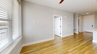 Unit 260 in Charlotte, NC (28206) is a well-appointed 2-bedroom, 3-bathroom single-floor apartment offering 920 square feet of thoughtfully designed living space. Warm hardwood-style flooring flows consistently throughout, complementing the neutral gray walls and clean white trim found in every room.

The open-concept kitchen and living area serves as the heart of the unit. The kitchen features a large central island with a white quartz countertop and an undermount sink, white upper cabinetry, gray lower cabinetry with matte black hardware, a white subway tile backsplash, stainless steel appliances, and stylish pendant lighting. An adjacent walk-in pantry provides ample storage.

The primary bedroom measures 170 square feet and includes a ceiling fan, built-in shelving, and direct balcony access. The second bedroom also benefits from natural light via a large window and balcony-facing door. Both rooms feature ceiling fans and generous closet space. The private balcony offers open outdoor views of the surrounding Charlotte neighborhood.

All three bathrooms showcase a cohesive modern aesthetic with gray vanity cabinetry, white quartz countertops, matte black fixtures, large-format white tile, and wood-look flooring. Two bathrooms include a tub-shower combination, while one features a glass-enclosed walk-in shower. A dedicated in-unit laundry room houses a full-size top-load washer and dryer.