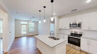 Located in Huntersville, NC, this single-floor, 2-bedroom, 2-bathroom home offers a thoughtfully designed layout with modern finishes throughout. Warm hardwood-style flooring flows seamlessly across every room, creating a cohesive and inviting atmosphere.

The open-concept kitchen and living area serves as the heart of the home. The kitchen is equipped with stainless steel appliances, crisp white shaker cabinetry, and granite countertops that extend across a spacious center island with a double sink and pendant lighting above — ideal for both cooking and casual dining.

The primary bedroom is generously sized and features a ceiling fan, large windows with outdoor views, and access to a private balcony overlooking a lush, tree-lined landscape. The primary bathroom includes a walk-in closet, a glass-enclosed shower, and a granite-topped vanity. The second bathroom mirrors this refined aesthetic, offering a full tub-shower combination and a well-lit vanity with granite counters.

The second bedroom is bright and versatile, featuring clean white walls and ample natural light. Both hallways provide functional connectivity throughout the home. The private balcony offers peaceful views of tall pine trees and green open space, adding a tranquil natural backdrop to this well-finished residence.