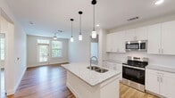 Located in Huntersville, NC, this single-floor, 2-bedroom, 2-bathroom home offers a thoughtfully designed layout with modern finishes throughout. Warm hardwood-style flooring flows seamlessly across every room, creating a cohesive and inviting atmosphere.

The open-concept kitchen and living area serves as the heart of the home. The kitchen is equipped with stainless steel appliances, crisp white shaker cabinetry, and granite countertops that extend across a spacious center island with a double sink and pendant lighting above — ideal for both cooking and casual dining.

The primary bedroom is generously sized and features a ceiling fan, large windows with outdoor views, and access to a private balcony overlooking a lush, tree-lined landscape. The primary bathroom includes a walk-in closet, a glass-enclosed shower, and a granite-topped vanity. The second bathroom mirrors this refined aesthetic, offering a full tub-shower combination and a well-lit vanity with granite counters.

The second bedroom is bright and versatile, featuring clean white walls and ample natural light. Both hallways provide functional connectivity throughout the home. The private balcony offers peaceful views of tall pine trees and green open space, adding a tranquil natural backdrop to this well-finished residence.