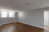 Located at 5500 N Main St in Fall River, MA, this two-bedroom, one-bathroom residence offers a well-organized single-floor layout designed for comfortable, everyday living. The interior is finished with durable wood-style flooring throughout, neutral gray walls, and clean white trim, creating a bright and cohesive aesthetic across every room.

The spacious living room receives natural light through multiple windows, giving the area an open, airy feel. It flows into a separate dining room, providing a clear distinction between living and eating areas. The galley-style kitchen is efficiently designed with ample white cabinetry, dark stone-look countertops, a stainless steel sink, and white appliances including a range and dishwasher. A dedicated entrance from the kitchen adds convenience.

The primary bedroom is generously sized and features hardwood-style flooring, natural light from a window, and access to two closets, offering excellent storage capacity. The second bedroom is also well-proportioned with its own window. The full bathroom includes a combined tub and shower, a vanity with countertop storage, and classic tile flooring. Additional highlights include a dedicated laundry area, a hallway, five closets total throughout the unit, and two entrance points for added accessibility.