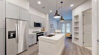 Located at 10400 Research Blvd in Austin, TX, this thoughtfully designed one-bedroom, one-bathroom residence makes excellent use of its compact footprint. The open living area welcomes you with light wood-look flooring, recessed lighting, and a set of French doors that flood the space with natural light and open onto a private patio overlooking a landscaped courtyard. The modern kitchen is a standout feature, showcasing gray shaker-style cabinetry, a white quartz waterfall island with an undermount sink, stainless steel appliances, a subway tile backsplash, and pendant lighting that adds a contemporary touch. The bedroom is a comfortable retreat, finished with plush carpet, a ceiling fan, and windows that bring in generous natural light and outdoor views. A dedicated walk-in closet with built-in shelving provides practical storage. The bathroom features gray cabinetry with white countertops, tile flooring, and a clean, modern aesthetic. The private patio, framed by metal railings, offers a relaxing outdoor space with views of the community's green courtyard. Clean white walls and a cohesive neutral palette throughout give the entire residence a bright, airy, and move-in-ready feel.
