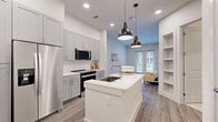 Located at 10400 Research Blvd in Austin, TX, this thoughtfully designed one-bedroom, one-bathroom residence makes excellent use of its compact footprint. The open living area welcomes you with light wood-look flooring, recessed lighting, and a set of French doors that flood the space with natural light and open onto a private patio overlooking a landscaped courtyard. The modern kitchen is a standout feature, showcasing gray shaker-style cabinetry, a white quartz waterfall island with an undermount sink, stainless steel appliances, a subway tile backsplash, and pendant lighting that adds a contemporary touch. The bedroom is a comfortable retreat, finished with plush carpet, a ceiling fan, and windows that bring in generous natural light and outdoor views. A dedicated walk-in closet with built-in shelving provides practical storage. The bathroom features gray cabinetry with white countertops, tile flooring, and a clean, modern aesthetic. The private patio, framed by metal railings, offers a relaxing outdoor space with views of the community's green courtyard. Clean white walls and a cohesive neutral palette throughout give the entire residence a bright, airy, and move-in-ready feel.