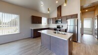 Located at 18417 E Appleway Ave in Spokane Valley, WA, this thoughtfully designed unit offers a single-level layout with an open, airy feel defined by striking vaulted ceilings that amplify the sense of space throughout. The open-concept kitchen serves as the heart of the home, showcasing rich dark-toned cabinetry, a large center island with a built-in sink and light countertops, stainless steel appliances including a range, microwave, and refrigerator, and stylish pendant lighting that adds a warm, modern touch. Light wood-style flooring runs throughout the main living areas, complementing the neutral color palette and contributing to the bright, clean aesthetic. The living area is generously proportioned, benefiting from abundant natural light through large windows and sliding glass door access to a private balcony with outdoor views. A dedicated bedroom features plush carpeting, soaring ceilings, a wall-mounted mini-split system for personalized climate control, and its own balcony access. The bathroom is well-appointed with dark cabinetry, light countertops, a full tub-shower combination, and a window for natural light. Overall, the unit presents a fresh, contemporary ambiance with quality finishes and functional design throughout.