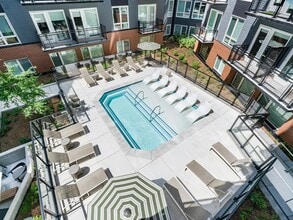 Courtyard pool with in-water loungers, sun seating, and surrounding balconies creating a social outdoor setting for warm-weather downtime. - Modera H Street
