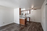 Located at 16850 Jasmine St in Victorville, California, this single-floor unit offers a clean, functional layout with consistent wood-look flooring throughout every room, creating a cohesive and easy-to-maintain living environment.

The kitchen is efficiently designed with a galley-style configuration, featuring warm wood-toned cabinetry paired with white lower cabinets and matching white appliances, including a range and refrigerator. A double-basin sink with a light stone-look countertop provides ample workspace. The kitchen opens to the living area via a peninsula counter with matching wood cabinetry, making it ideal for casual dining or additional prep space.

The living area is bright and open, with neutral white walls, a ceiling fan with integrated lighting, and a visible HVAC vent. The space flows naturally from the kitchen peninsula toward the bedroom hallway, providing a practical and airy layout.

The bedroom is a well-proportioned room with white walls, wood-look flooring, and a window offering views of the surrounding greenery, allowing for natural light throughout the day.

The bathroom is a full bath featuring a tub and shower combination equipped with accessibility grab bars and a curtain rod, a single-basin vanity with storage drawers, a large mirror, and wood-look flooring that ties seamlessly to the rest of the unit.