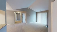 Located at 4860 Greystone Ln in Mount Pleasant, Michigan, this single-floor residence offers a well-organized layout designed for comfortable everyday living. The main living area immediately impresses with soaring vaulted ceilings that create a sense of openness and airiness. A corner fireplace serves as a focal point, adding warmth and character to the space, while large sliding glass doors fitted with vertical blinds allow for generous natural light and outdoor access. Neutral-toned carpet flows throughout the living and bedroom areas, contributing to a cohesive and understated aesthetic. The living area transitions naturally into a dedicated dining space, illuminated by an elegant chandelier. A pass-through window connects the dining area to the kitchen, which features light wood cabinetry, granite-style countertops, wood-look flooring, and white appliances including a refrigerator and range. The bedrooms are well-proportioned, each with carpeted floors, neutral gray walls, and windows fitted with blinds that provide natural light. The bathrooms include wood-look flooring, a tub/shower combination, and a vanity with a large mirror and warm overhead lighting. A hallway connects the private sleeping quarters, providing a clear and functional separation from the main living spaces.