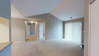 Located at 4860 Greystone Ln in Mount Pleasant, Michigan, this single-floor residence offers a well-organized layout designed for comfortable everyday living. The main living area immediately impresses with soaring vaulted ceilings that create a sense of openness and airiness. A corner fireplace serves as a focal point, adding warmth and character to the space, while large sliding glass doors fitted with vertical blinds allow for generous natural light and outdoor access. Neutral-toned carpet flows throughout the living and bedroom areas, contributing to a cohesive and understated aesthetic. The living area transitions naturally into a dedicated dining space, illuminated by an elegant chandelier. A pass-through window connects the dining area to the kitchen, which features light wood cabinetry, granite-style countertops, wood-look flooring, and white appliances including a refrigerator and range. The bedrooms are well-proportioned, each with carpeted floors, neutral gray walls, and windows fitted with blinds that provide natural light. The bathrooms include wood-look flooring, a tub/shower combination, and a vanity with a large mirror and warm overhead lighting. A hallway connects the private sleeping quarters, providing a clear and functional separation from the main living spaces.