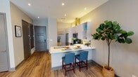 Located at 319–347 Nichols St in Fort Worth, TX, this contemporary single-floor residence showcases a thoughtfully designed open-concept layout with modern finishes throughout. Wood-look flooring flows seamlessly across the entire space, creating a warm and cohesive aesthetic.

The kitchen is a standout feature, equipped with stainless steel appliances — including a French door refrigerator, electric range with overhead hood, and microwave — complemented by crisp white cabinetry, a subway tile backsplash, quartz countertops, and recessed lighting. A peninsula with an extended breakfast bar offers seating for two, making it ideal for casual dining and entertaining.

The open living area is anchored by a wall-mounted electric fireplace and benefits from abundant natural light through large windows and a glass-panel door. Teal accent walls and bold crown molding add a distinctive design touch, while the space transitions smoothly into the bedroom area, separated by a structural column.

The bedroom features a ceiling fan, generous windows, and recessed lighting, fostering a bright and comfortable retreat. The full bathroom is finished with dark wood-look tile, a glass-enclosed walk-in shower, a wide vanity with an undermount sink, and a large mirror — combining style with practicality throughout.