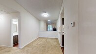 This single-story residence offers a well-organized layout with multiple rooms connected by a practical, flowing floor plan. The living area serves as the heart of the home, featuring a ceiling fan, a fireplace with a simple surround, and a large sliding glass door that brings in natural light and provides views of the outdoors. Adjacent to the living area, a pass-through with a marble-style countertop connects to the kitchen, creating an open, communicative feel between spaces.

The kitchen is designed in a galley configuration, finished with dark wood cabinetry, marble-style countertops, hardwood-style flooring, and black appliances including a range, microwave, and dishwasher. A louvered closet door nearby offers convenient storage access.

The bedrooms are carpeted throughout and feature ceiling fans, textured ceilings, and vaulted or angled ceiling details in select rooms that enhance the sense of spaciousness. Natural light enters through windows fitted with blinds. One bedroom includes a large mirror wall and direct access to a bathroom, while another offers a walk-in closet. The neutral color palette of warm beige and white tones gives the entire residence a clean, cohesive, and move-in-ready appearance.