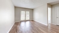 This single-story, 2-bedroom, 1-bathroom residence in Jonesboro, Arkansas offers a well-organized and functional layout designed for comfortable everyday living. The living room features warm wood-look flooring, neutral gray walls, and a textured ceiling, with a pass-through window connecting to the kitchen and French doors that invite natural light and provide outdoor access. The galley-style kitchen is efficiently arranged with gray cabinetry, white laminate countertops, white appliances including a range and refrigerator, and a stainless steel sink — all set atop matching wood-look flooring. Both bedrooms are carpeted and feature large windows that bring in ample natural light and views of the surrounding greenery, creating a calm and restful atmosphere. The six-panel doors and neutral color palette throughout lend a clean, cohesive look to the space. The full bathroom includes a tub-shower combination with updated chrome fixtures. A dedicated laundry area with washer and dryer hookups and overhead wire shelving adds everyday convenience. Two hallways connect the various areas of the home efficiently, complemented by a closet for additional storage. This residence offers a practical and well-appointed layout in a convenient Jonesboro location.