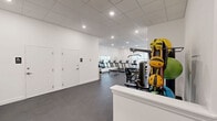 Located at 268 Market St in South Burlington, Vermont, this fitness center offers a thoughtfully designed exercise room spread across a single floor. The space features clean white walls, a drop-panel ceiling with recessed lighting, and durable dark rubber flooring suited for high-traffic athletic use.

The room is comprehensively equipped to support a wide range of workout styles. Cardio options include multiple treadmills and stationary cycling bikes with digital displays. For strength training, the space provides a selection of selectorized machines for targeted muscle groups, a multi-function cable station, a rack of dumbbells spanning various weights, and a flat workout bench. A dedicated functional training area along one wall is stocked with medicine balls, stability balls in multiple sizes, resistance accessories, and exercise mats organized neatly on storage racks.

A wall-mounted split air conditioning unit ensures climate control throughout the room, while a baseboard heater along one wall provides supplemental heating during Vermont's colder months. A large wall mirror enhances the sense of openness and allows users to monitor their form. Natural light filters in through a window, adding brightness to the well-lit interior. Storage lockers are also available within the space. The overall layout is open and organized, providing ample room to move freely between equipment stations.