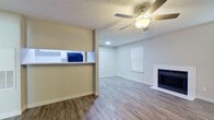 This 2-bedroom, 2-bathroom single-floor residence offers a thoughtfully arranged layout that maximizes its efficient footprint. The living room serves as the heart of the home, featuring durable wood-look flooring, a ceiling fan with integrated lighting, a textured ceiling, and a classic fireplace framed in white — creating a warm and inviting atmosphere. Natural light filters in through blinded windows, enhancing the open feel of the space. A pass-through opening connects the living area to the kitchen, which is outfitted with white cabinetry, light countertops, black appliances including an electric range and dishwasher, and an overhead vent hood — offering both style and practicality. The two bedrooms continue the wood-look flooring theme and are brightened by natural light through blinded windows; the primary bedroom includes a ceiling fan, while both rooms provide ample space for furnishing. A dedicated closet with built-in shelving adds convenient storage. Both bathrooms are identically appointed with white vanities featuring light stone-style countertops, a large mirror, and a full tub-shower combination. A connecting hallway ties all areas together, completing this clean and cohesive single-level home.