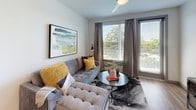 This single-floor residence offers a thoughtfully designed open-concept layout with contemporary finishes throughout. The kitchen is a standout feature, equipped with a full suite of stainless steel appliances, including a refrigerator, range, and microwave. Light wood-tone cabinetry extends to the ceiling, complemented by a white quartz peninsula with bar seating and a classic subway tile backsplash. A pendant light anchors the space, while wood-look flooring runs throughout the main living areas.

The kitchen flows seamlessly into the living area, which benefits from large windows and a sliding glass door that invite natural light and offer views of surrounding greenery. The bedroom is carpeted for comfort and features a generous window with outdoor views, providing a bright and airy atmosphere. A second bedroom or additional sleeping area is also present.

The bathroom is well-appointed with light wood cabinetry, a white countertop vanity, wood-look flooring, and a tub-shower combination with tile surround. A dedicated in-unit laundry closet with a stacked washer and dryer adds everyday convenience, rounding out this efficiently designed and modern living space.
