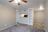 This single-floor residence offers a practical and well-organized layout designed for comfortable everyday living. The kitchen is equipped with black appliances, including a range and refrigerator, complemented by two-tone cabinetry featuring gray lower cabinets and white uppers, light stone-look countertops, and wood-look vinyl flooring that extends into the adjoining areas. A structural column visually separates the kitchen from the living space, which transitions to carpeted flooring and connects to a hallway leading to the rest of the unit.

The bedrooms are carpeted throughout and each feature ceiling fans with integrated lighting. Several rooms benefit from natural light through windows fitted with blinds, and at least one bedroom includes a walk-in closet. Two rooms provide access to an outdoor space through sliding glass doors dressed with vertical blinds, adding versatility to those rooms. A thermostat is present in one of these rooms, indicating individual climate control.

The bathroom features a full soaking tub and shower combination, white subway tile surround with a decorative mosaic accent border in neutral and brown tones, and a clean, minimal aesthetic throughout. Overall, the space presents a neutral palette with consistent finishes that create a cohesive and functional living environment.