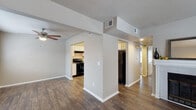 This single-story residence offers a thoughtfully designed layout that balances open communal spaces with comfortable private areas. The living room serves as the heart of the home, featuring rich, dark hardwood-style flooring, neutral gray walls, a textured ceiling, and a ceiling fan. Natural light flows in through a large window with blinds, and the entry door is conveniently located within the space, creating a welcoming arrival experience.

The kitchen is well-equipped and visually striking, showcasing an abundance of white cabinetry that extends to the upper walls, providing generous storage throughout. A double-basin stainless steel sink anchors the countertops, complemented by a full suite of black appliances — including a gas range, dishwasher, and refrigerator — all set against durable hardwood-style flooring that carries through from the living area.

The bedrooms offer plush carpeted flooring and neutral wall tones. One bedroom features a wide sliding-door closet with recessed lighting overhead, while another benefits from a large window that allows ample natural light. The bathroom is clean and functional, equipped with a full tub-shower combination and tile surround.

Throughout the space, a cohesive neutral palette, consistent flooring choices, and practical finishes create a comfortable and move-in-ready environment.