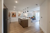 Located in Cape Coral, FL, this well-appointed 2-bedroom, 2-bathroom residence offers a thoughtfully designed single-floor layout across a comfortable footprint. Light wood-style flooring flows throughout, tying the space together with a warm, cohesive aesthetic.

The open-concept kitchen is a standout feature, showcasing stainless steel appliances, warm wood cabinetry extending to the ceiling, a white quartz peninsula with seating, a white tile backsplash, and stylish black pendant lighting — ideal for both daily living and entertaining.

The living room is bright and inviting, with a sliding glass door that opens onto a private balcony overlooking the surrounding area, filling the room with natural light.

The spacious primary bedroom features a ceiling fan, a large window with outdoor views, and access to a dedicated closet. The en-suite bathroom includes a dual-sink vanity with white countertops, warm wood cabinetry, and light wood flooring. A second bedroom and full bathroom offer additional comfort and flexibility.

Both closets feature wire shelving systems for organized storage. The in-unit laundry room houses a full-size washer and dryer with overhead shelving. A hallway connects all rooms, completing this clean, modern layout.