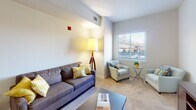 Located at 331 Justison Street in Wilmington, Delaware, this single-floor residential unit offers a thoughtfully designed layout that balances functionality and comfort. The open-concept kitchen is a standout feature, equipped with dark espresso cabinetry reaching toward the ceiling, stainless steel appliances including a refrigerator, range, microwave, and dishwasher, complemented by dark countertops and a breakfast bar that seamlessly connects to the main living area. The hardwood flooring in the kitchen transitions into plush carpeting throughout the living spaces, adding warmth underfoot. The living room is bright and inviting, benefiting from natural light streaming through a large window with views of the surrounding Wilmington streetscape. The bedroom is a calm, neutral retreat, also featuring a window that draws in natural light and offers urban views. The bathroom is clean and functional, appointed with white tile surrounding a full soaking tub and shower combination, chrome fixtures, and light tile flooring. Throughout the unit, the design palette of neutral whites and warm tones creates a cohesive, modern aesthetic suited to urban residential living in the heart of Wilmington's Riverfront district.
