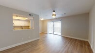 This single-floor unit offers a clean, contemporary layout designed for comfortable everyday living. The open-concept living and dining area is finished with light hardwood-style flooring, neutral walls, and a ceiling fan, creating a bright and airy atmosphere. A large sliding glass door fitted with vertical blinds floods the space with natural light and provides access to an outdoor area beyond.

The kitchen is well-equipped with white cabinetry, granite-look countertops, and a full suite of stainless steel appliances including a range, microwave, and refrigerator. A pass-through window connects the kitchen to the main living area, enhancing the open feel and making the space ideal for everyday interaction.

The bedroom is generously sized, finished with plush carpeting and a ceiling fan, and benefits from a natural light source through a window with blinds. Notably, the bedroom connects directly to both a full bathroom and a walk-in closet, offering convenient and practical storage solutions.

The bathroom is neatly appointed with white subway tile in the tub-shower surround, a granite-top vanity with white cabinetry, and hardwood-style flooring that ties the space together cohesively. Overall, the unit presents a well-balanced combination of functionality and modern design.