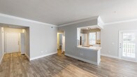 This single-floor residence offers a clean, modern aesthetic highlighted by wood-look flooring that flows seamlessly throughout the entire space. The open-concept living area is anchored by neutral gray walls, crisp white crown molding, and abundant natural light streaming through blinds-fitted windows. A pass-through kitchen opens directly to the living space, featuring white shaker-style cabinetry, light quartz countertops, gray subway tile backsplash, and a full suite of stainless steel appliances including a refrigerator, electric range, over-the-range microwave, and dishwasher. A single-basin sink with a contemporary faucet completes the kitchen workspace. The bedrooms are generously sized, each equipped with ceiling fans and large windows that bring in natural light. The primary bedroom provides direct access to a bathroom with white vanity cabinetry and a tiled tub-shower combination. A second full bathroom mirrors this finish level, featuring warm-toned tile surround and a soaking tub. Connecting hallways are well-lit and efficiently laid out. Throughout the space, consistent use of soft gray tones, white trim, and warm wood-look flooring creates a cohesive, inviting atmosphere that is both modern and comfortable.
