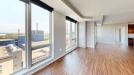 Located on the 15th floor at 801 S Washington Ave in downtown Minneapolis, this two-bedroom, two-bathroom residence offers a well-appointed layout with thoughtful finishes throughout. The open-concept kitchen and living area is anchored by rich hardwood flooring and floor-to-ceiling windows that frame sweeping views of the Minneapolis skyline. A dramatic exposed concrete column adds an industrial design element to the bright, airy living space. The kitchen is outfitted with dark wood cabinetry, a white subway tile backsplash, stainless steel appliances including a gas range and French door refrigerator, and a central island with pendant lighting — ideal for both cooking and entertaining. The spacious primary bedroom features plush carpeting, a ceiling fan, and access to a walk-in closet with built-in shelving and hanging rods. A second bedroom also includes carpet flooring and large windows. The two bathrooms are finished with white subway tile; one features a sleek glass-enclosed walk-in shower with grey stone-look tile flooring, while the other includes a full soaking tub and shower combination. Each bedroom is served by its own dedicated closet, providing generous storage throughout this well-designed downtown residence.